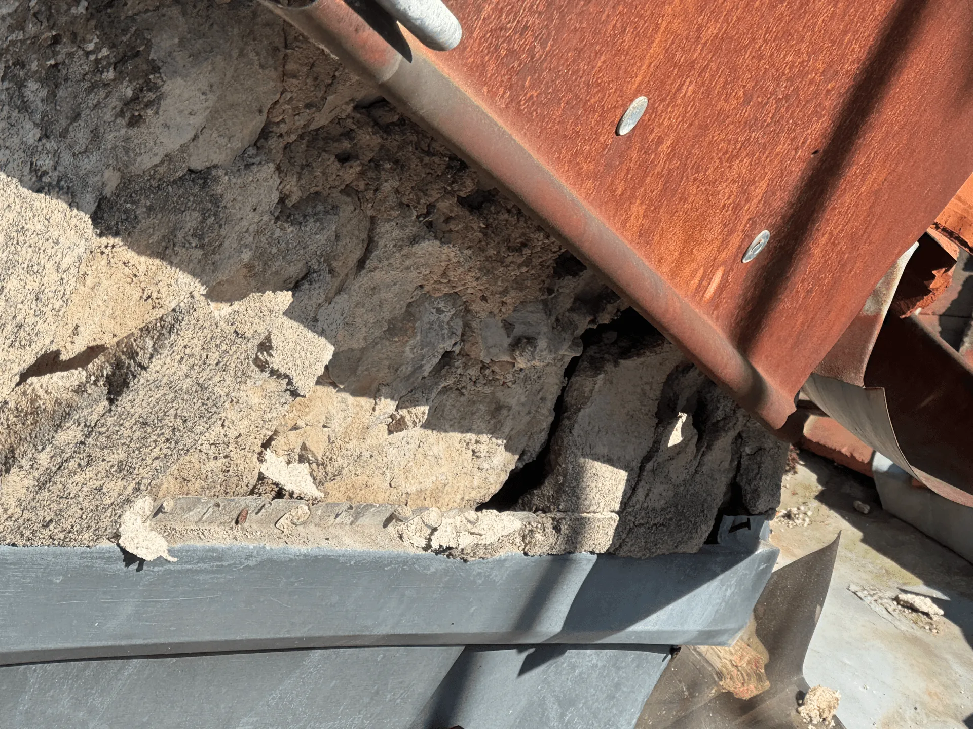 Gros plan d’un raccord en zinc au pied de tuiles et d’un mur maçonné