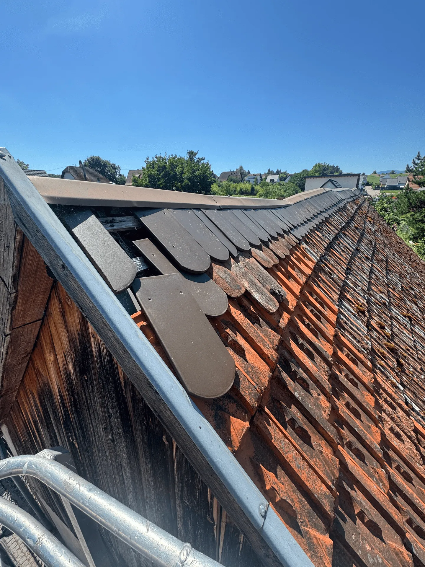 Détail d’une rive métallique et de tuiles plates au sommet d’une toiture